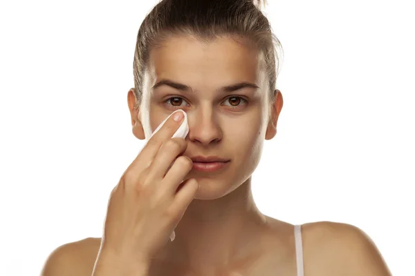 Mujer joven limpiando su cara con una toallita húmeda sobre fondo blanco — Foto de Stock