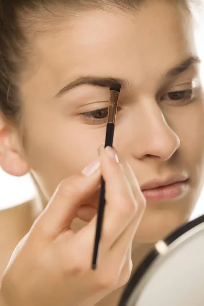 closeup of woman shaping her eyebrows with brush