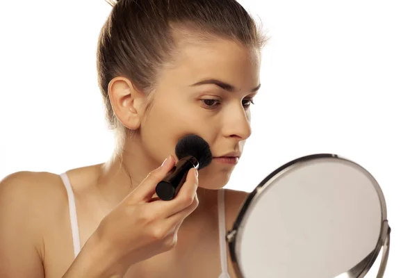Portrait of young woman applying powder foundation with brush on — Stok Foto