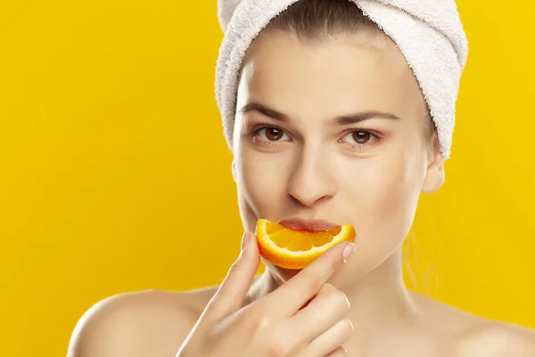 Portrait of young shirtles beautiful woman eating a orange on ye — Stock Photo, Image