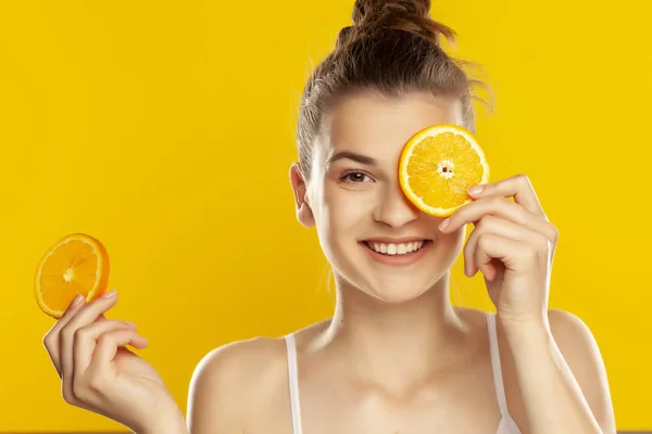 Young beautiful woman holding slice of orange in front of her ey — Stock Photo, Image