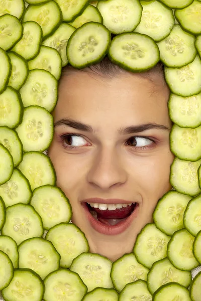 Young beautiful happy woman posing with slices of cucumber aroun — ストック写真