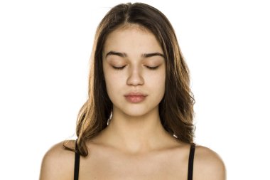 Makyajsız ve beyaz arka planda kapalı gözleri olan güzel bir kadın.