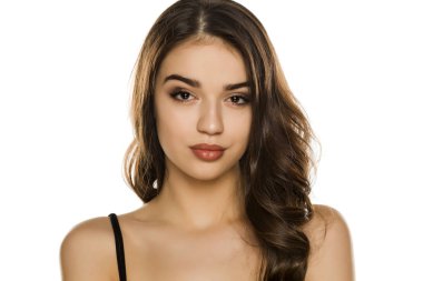 Makyajlı genç bir kadın, beyaz arka planda poz veriyor.