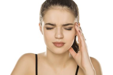 Beyaz arka planda baş ağrısı olan genç bir kadın.