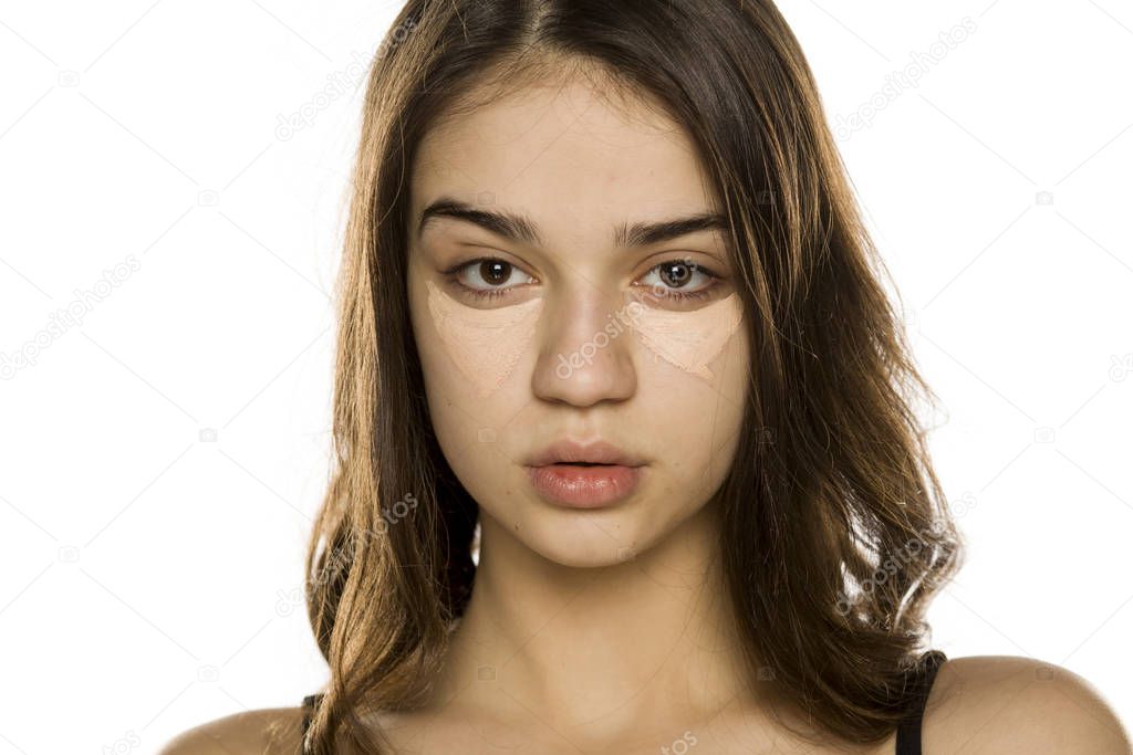 Young beautiful woman with concealer, posing on white background