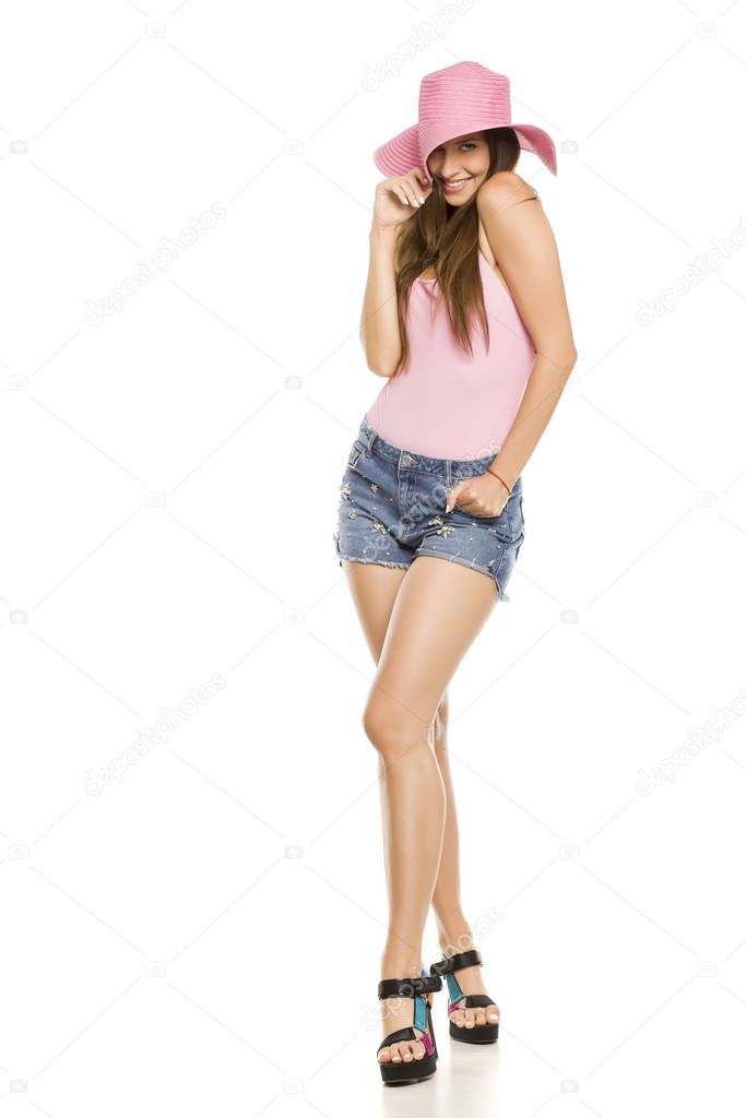 Young lady with hat and shorts posing on white background