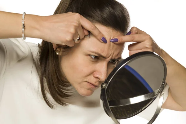 Uma Mulher Sauezing Sua Acne Espelho Fundo Branco — Fotografia de Stock