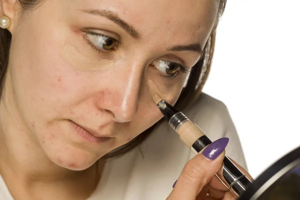 Mujer Joven Aplicando Corrector Cara Sobre Fondo Blanco — Foto de Stock