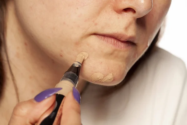 Mujer Joven Aplicando Corrector Cara Sobre Fondo Blanco — Foto de Stock