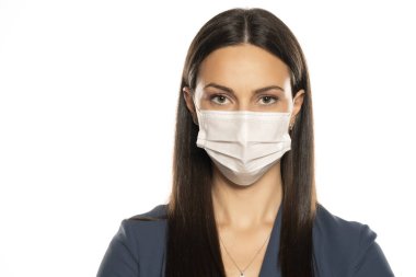 Beyaz arka planda yüzünde koruyucu maske olan güzel genç bir kadın.