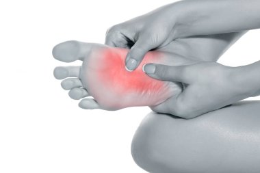 Beyaz arka planda acılı ayağına masaj yapan bir kadın.