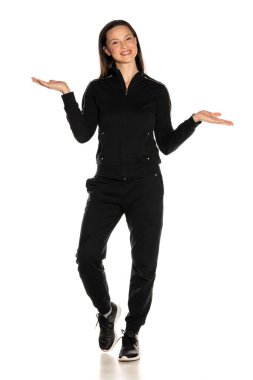 Young smiling woman in black track suit holding imaginary objects in her hands on white background clipart