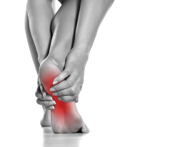 Beyaz arka planda acılı ayağına masaj yapan bir kadın.