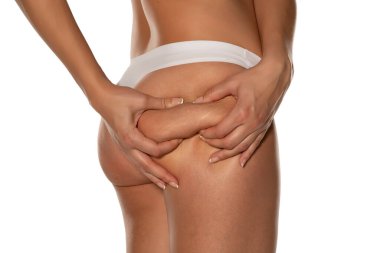 woman squeezing the cellulite on her butt on white background