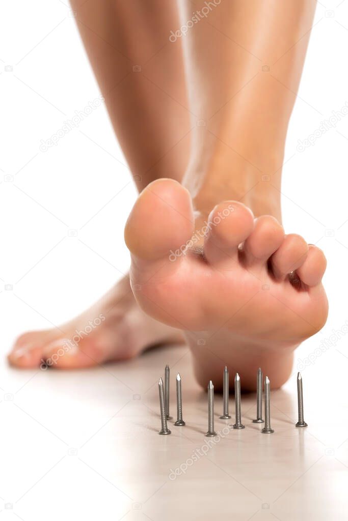 a woman's foot stepped on nails on white background