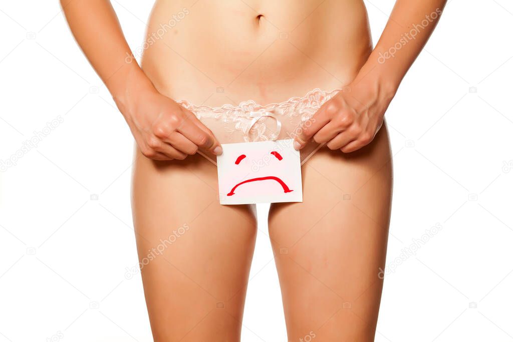 woman holds a drawn sad sign in front of her vagina