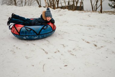 Küçük çocuk kışın tüp çörekte eğleniyor.