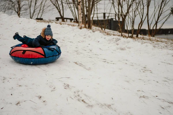 冬天的时候 可爱的男孩骑在结扎的小面包上下山 — 图库照片