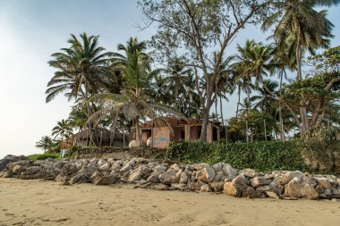 Beach poor huts, shacks among palm trees at tropical sunrise, Cabarete, Dominican Repiblic