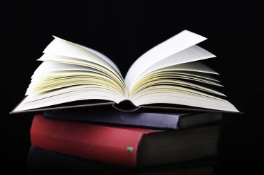 Kara arkaplanda izole birkaç kitap uçuyor.