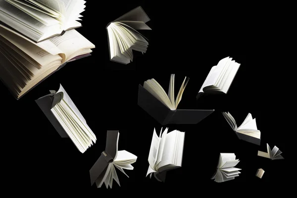 Kara arkaplanda izole birkaç kitap uçuyor.