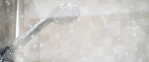 Islak cam pencerenin arkasında taze duş ve su damlaları. Duş başlığından su akıyor..