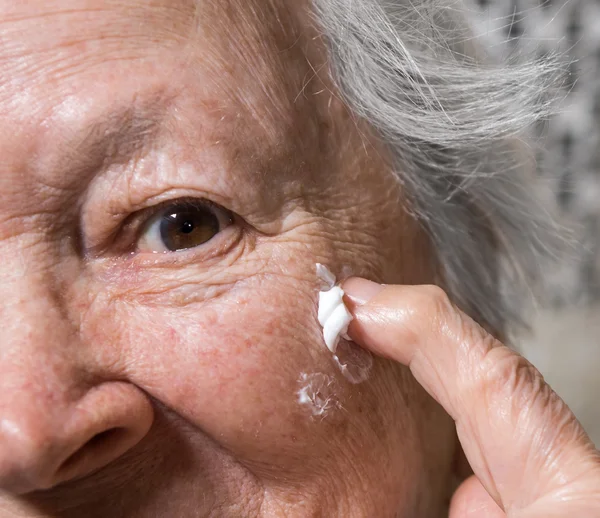 Alte Frau trägt Anti-Aging-Creme auf — Stockfoto