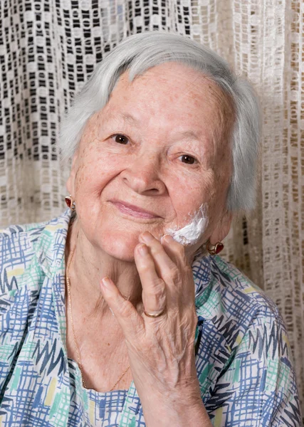 Oude vrouw toepassing van anti-aging crème — Stockfoto