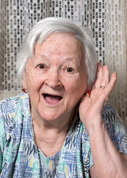 Old woman putting hand to her ear — Stock Photo, Image