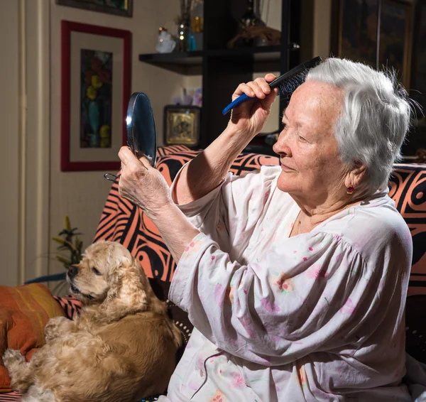 Oude lachende vrouw kammen haren — Stockfoto