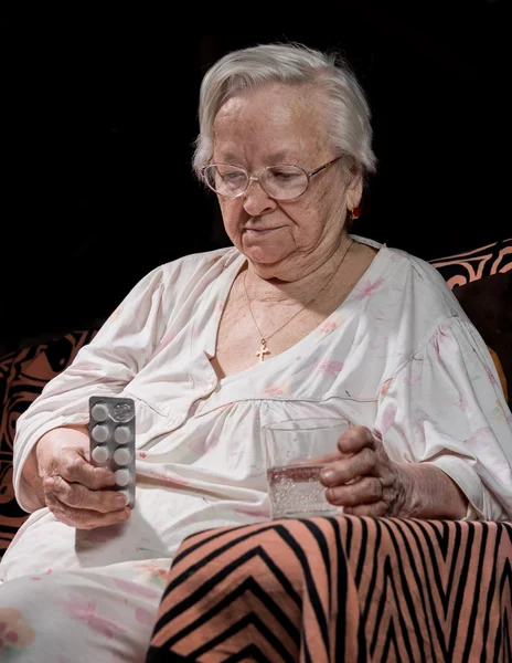 Старая грустная женщина держит таблетки — стоковое фото