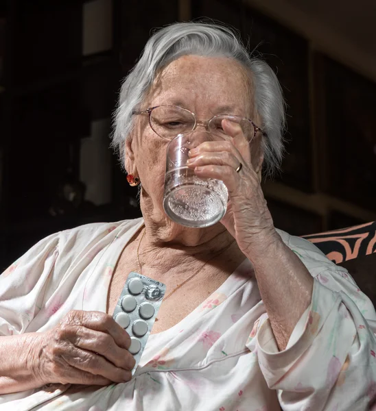 Старая грустная женщина держит таблетки — стоковое фото