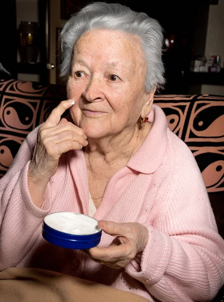 Alte Frau trägt Anti-Aging-Creme auf — Stockfoto