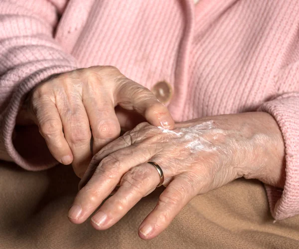 Vieille femme appliquant crème pour les mains — Photo