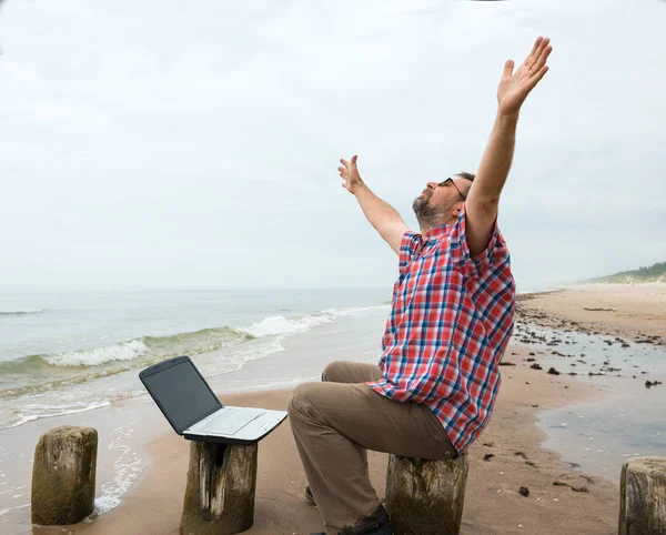 Ανώτερος ευτυχισμένος άνθρωπος που κάθονται στην παραλία με φορητό υπολογιστή — Φωτογραφία Αρχείου