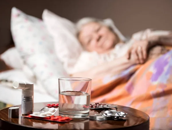 Sick old woman lying in bed at home — Stock Photo, Image