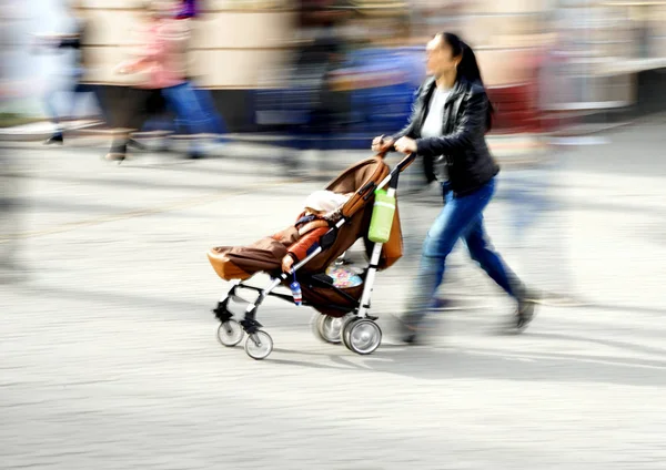 Junge Mutter mit kleinem Kind im Kinderwagen — Stockfoto