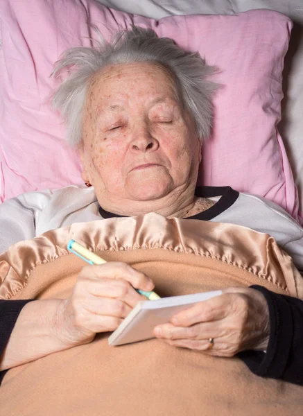 Stará žena ležela v posteli — Stock fotografie