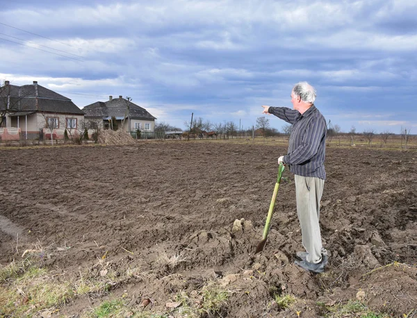 Farmer standing with a shovel on the field — Stock Photo, Image