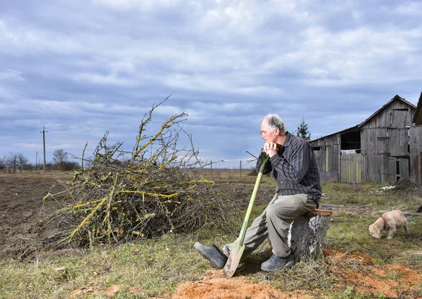 Agricultor sentado con una pala en el campo — Foto de Stock