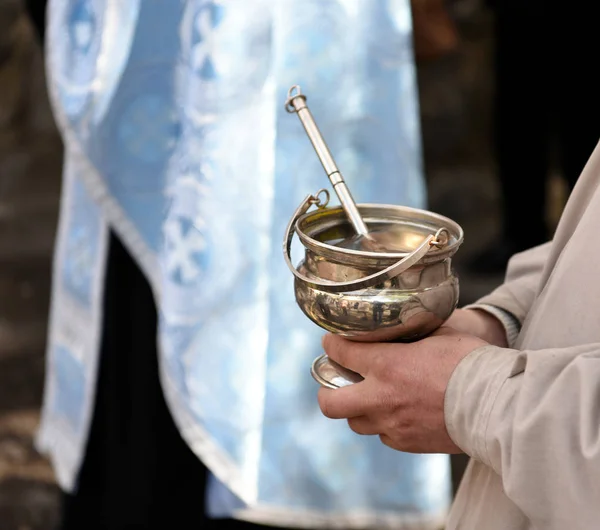 Male hands of priest  holding silver bowl and spoon — Stock Photo, Image