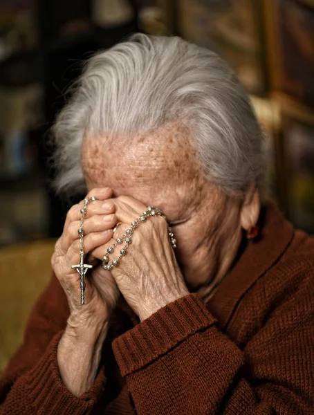 Anciana rezando y sosteniendo rosario de plata —  Fotos de Stock