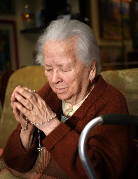 Old woman praying and  holding silver rosary — Stock Photo, Image