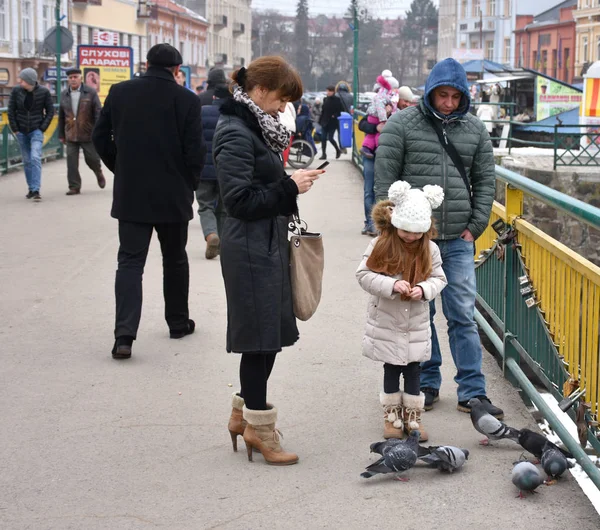 UZHGOROD,UKRAINE -FEBRUARY 17, 2017: People feeding the pigeons — Stock Photo, Image