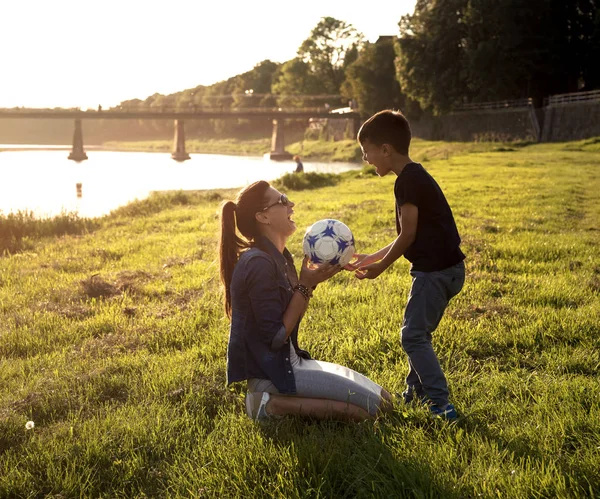 Feliz madre sonriente e hijos jugando con pelota de fútbol —  Fotos de Stock