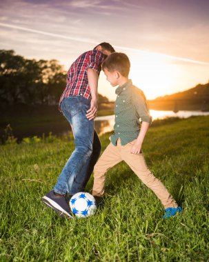 İki çocuk sahada futbol oynuyor. 