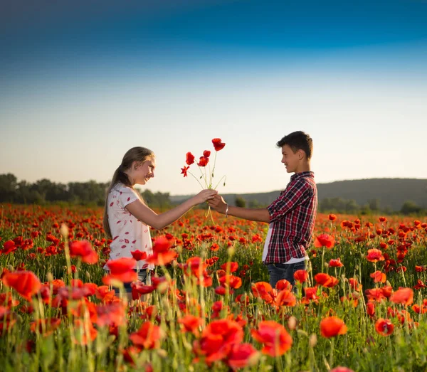 Подросток и девочка позируют на маковом поле — стоковое фото