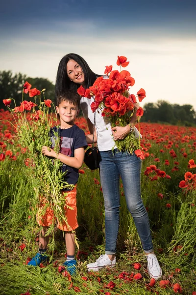 Smiling mother and son posing on the poppy field — Stock Photo, Image