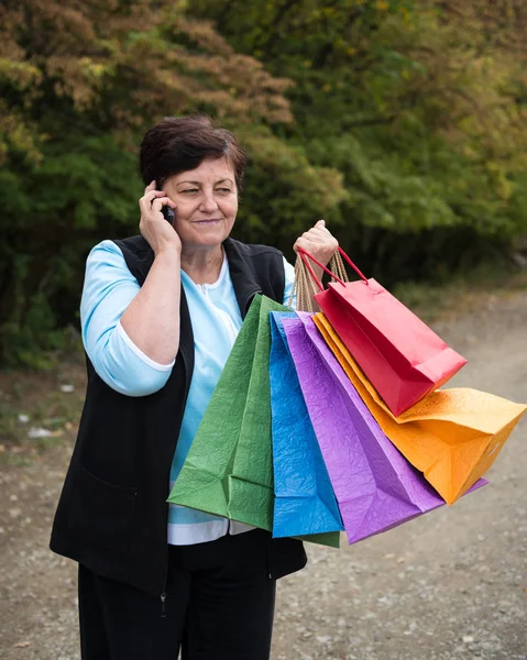 Smiling mature woman with shopping bags — Stock Photo, Image